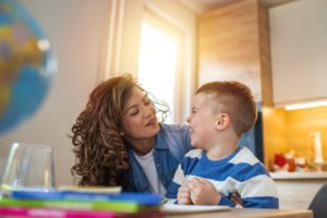 Mother helping her son doing homework and demonstrating the importance of early detecting of autism